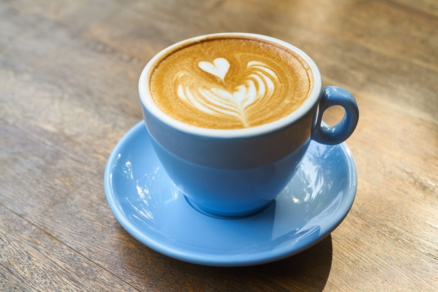 Heart-shaped latte art in a blue cup on a wooden table